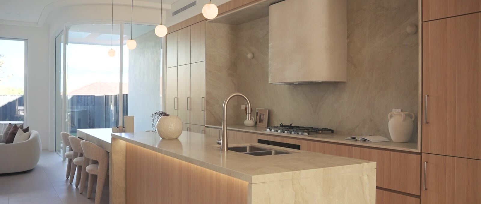Kitchen with timber island bench, stone splashback and pendant lighting